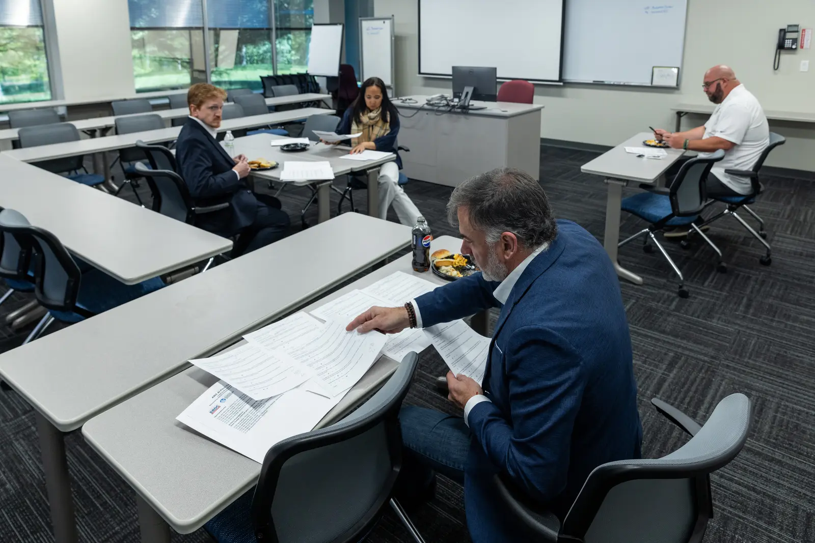 Jonas Bull at a classroom table covered in scoresheets, judging an AWS AI pitch competition