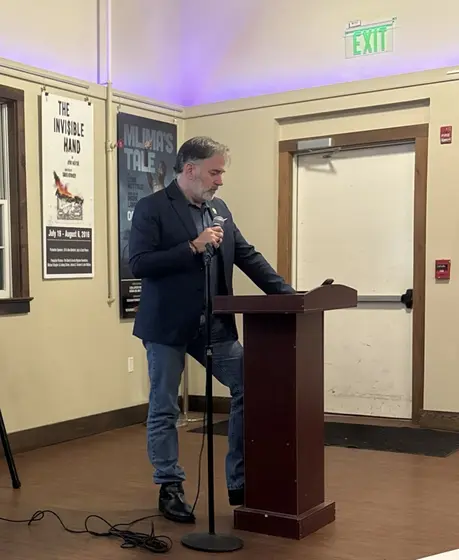 Speaking at a podium with a microphone in a small theater